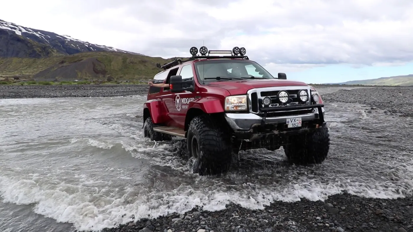 A super-jeep fording a glacial river